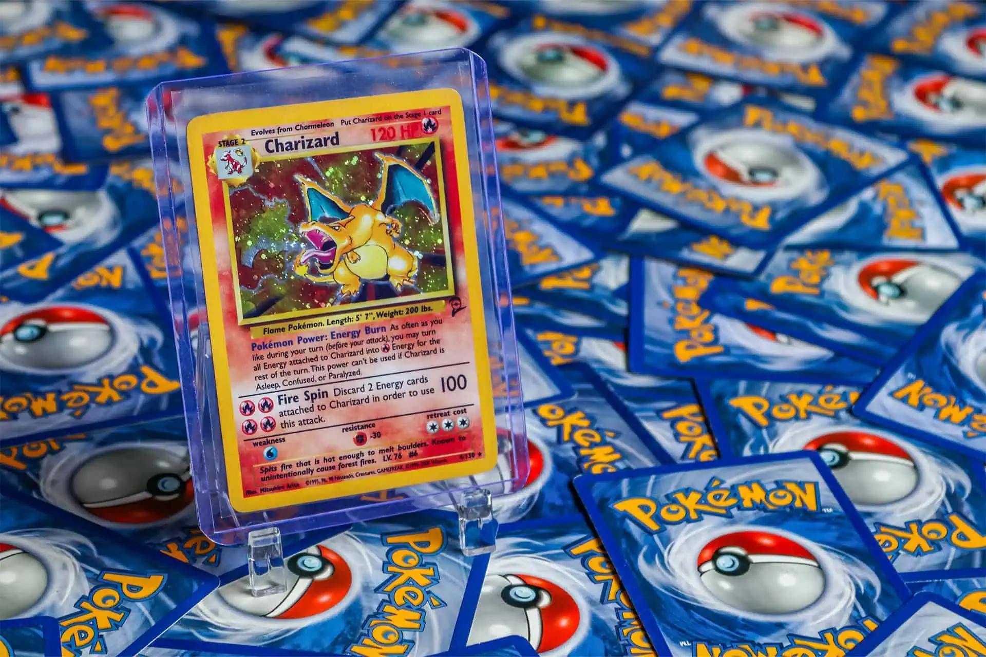 Carta Pokémon Charizard in custodia trasparente su sfondo di pacchetti Pokémon.